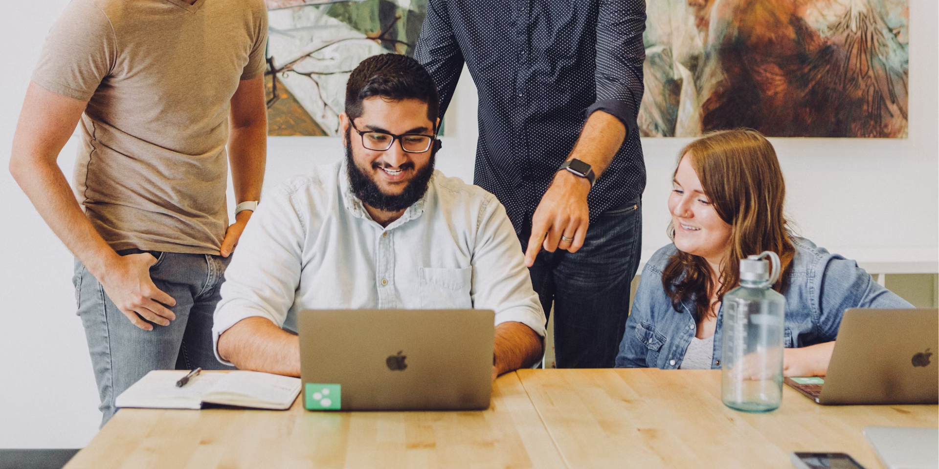 happy team surrounding a laptop